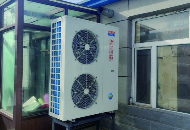 Snowfairy air-source heat pump installed beside a glass-fronted building